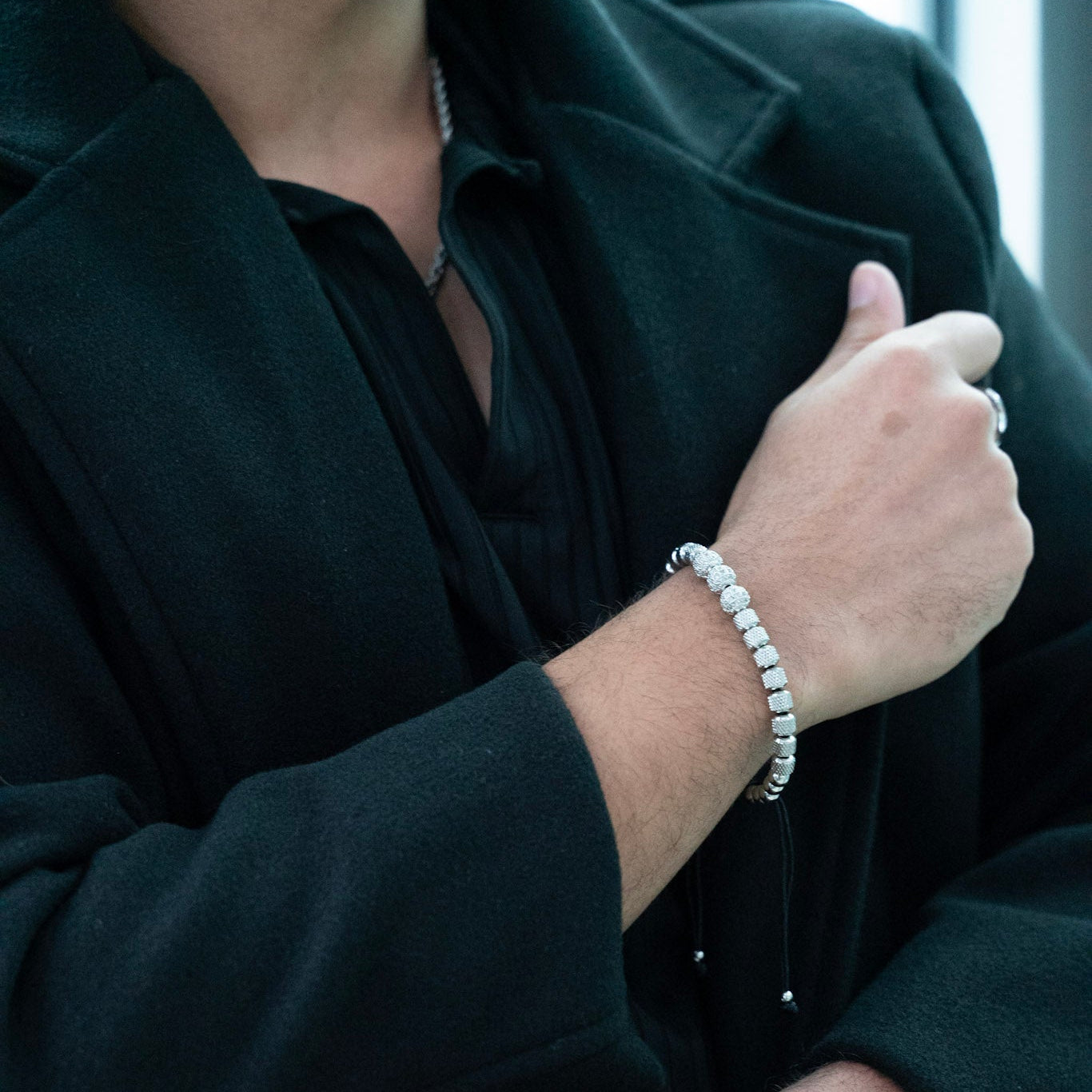Person wearing multiple bracelets and rings on a blurred background