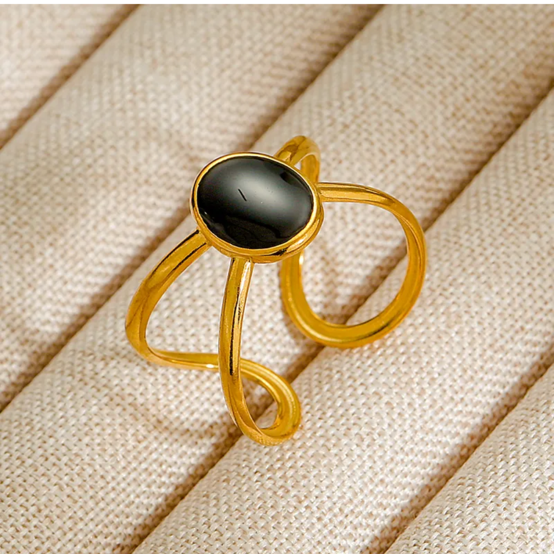 Gold ring with a black stone on a beige fabric background