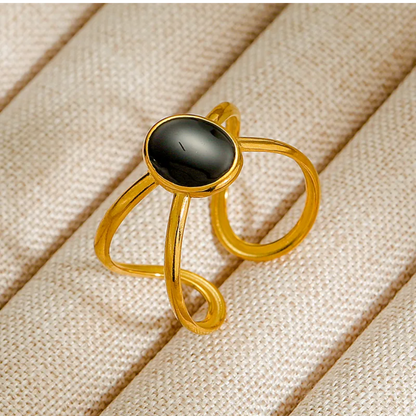 Gold ring with a black stone on a beige fabric background
