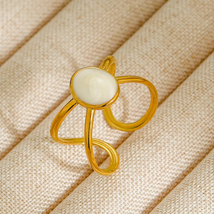 Gold ring with a white stone on a beige fabric background
