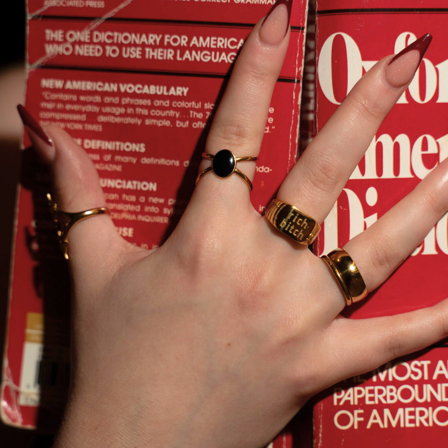 Hand with rings on a dictionary, with a focus on the text and design of the book.