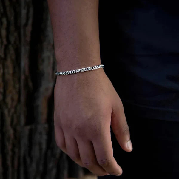 Hand wearing a silver bracelet against a dark background