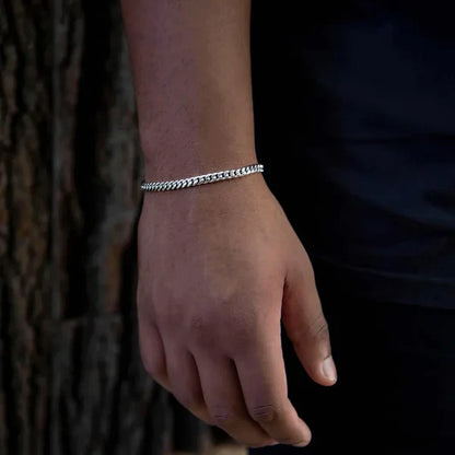 Hand wearing a silver bracelet against a dark background