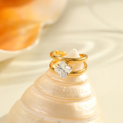 Gold ring with a diamond on a seashell against a soft beige background
