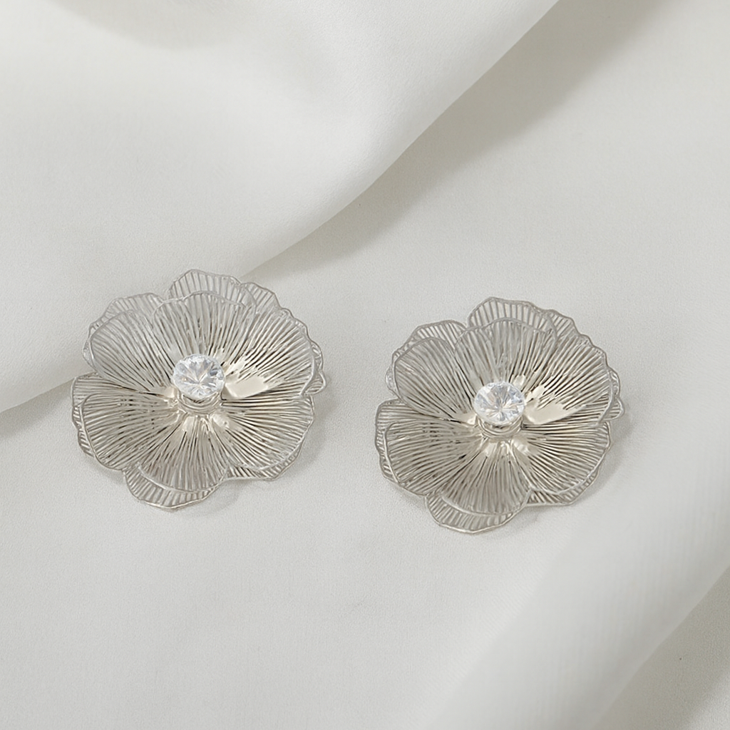 Silver floral earrings with a central gemstone on a light background