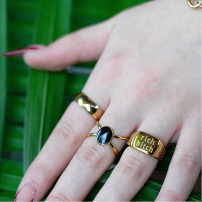 Hand with gold rings on a green leaf background