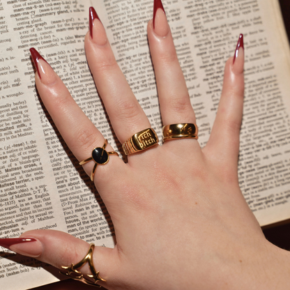 Hand wearing multiple gold rings on a textured surface