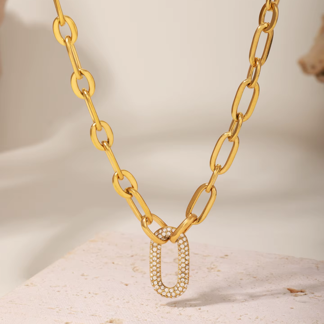 Gold chain necklace with a unique clasp on a neutral background