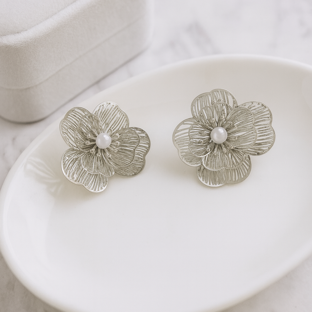 Silver floral earrings on a white dish with a marble background