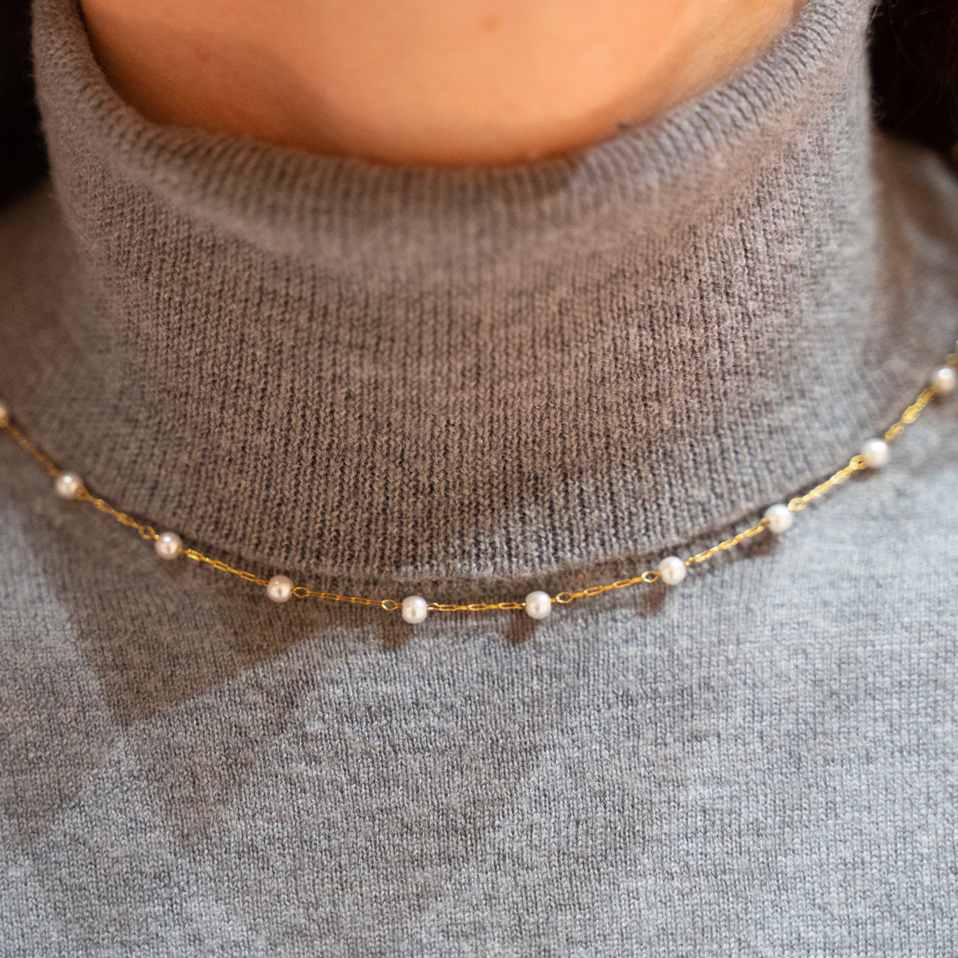 Necklace with small pearls on a gray sweater