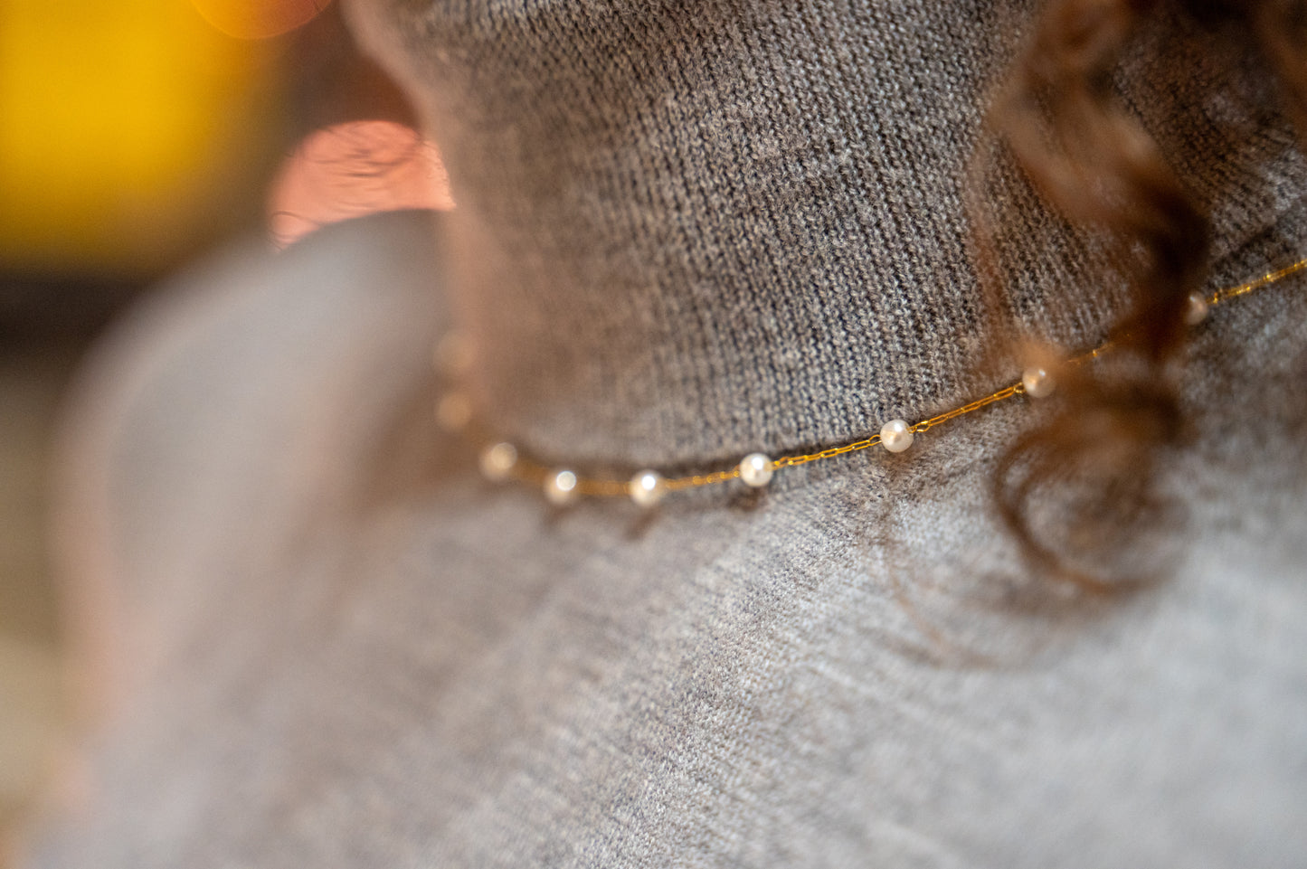 Close-up of a delicate gold necklace on a textured surface with blurred background