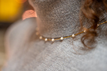 Close-up of a delicate gold necklace on a textured surface with blurred background