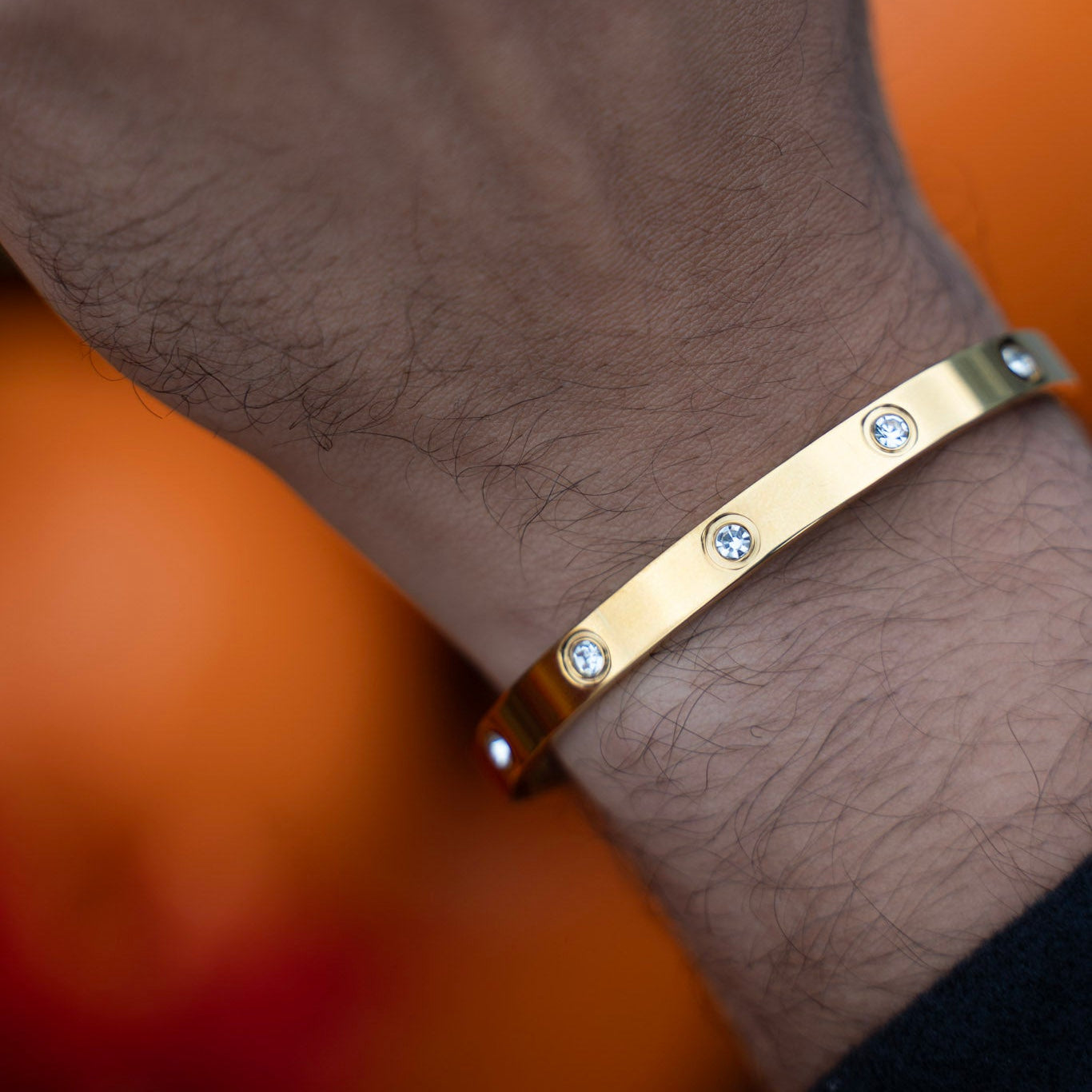 Gold bracelet with diamonds on a wrist against a blurred background