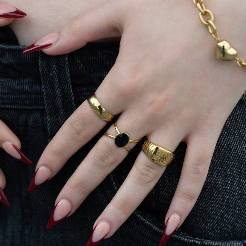 Close-up of a person's hands with gold rings and bracelets on a blurred background