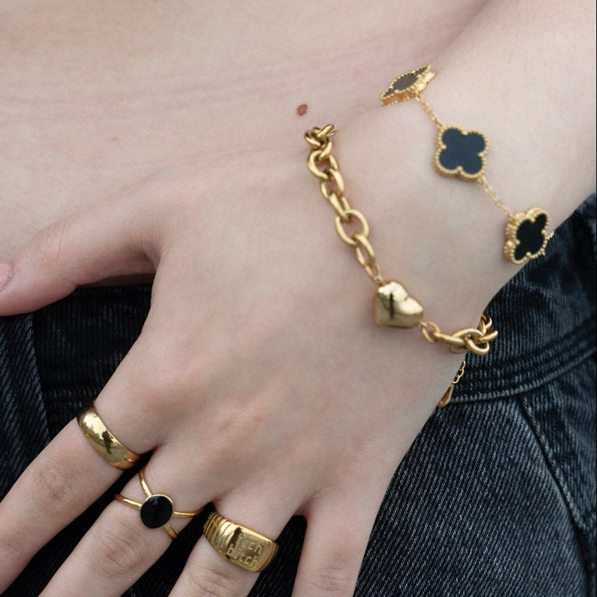 Close-up of a person's hands with gold rings and bracelets on a blurred background