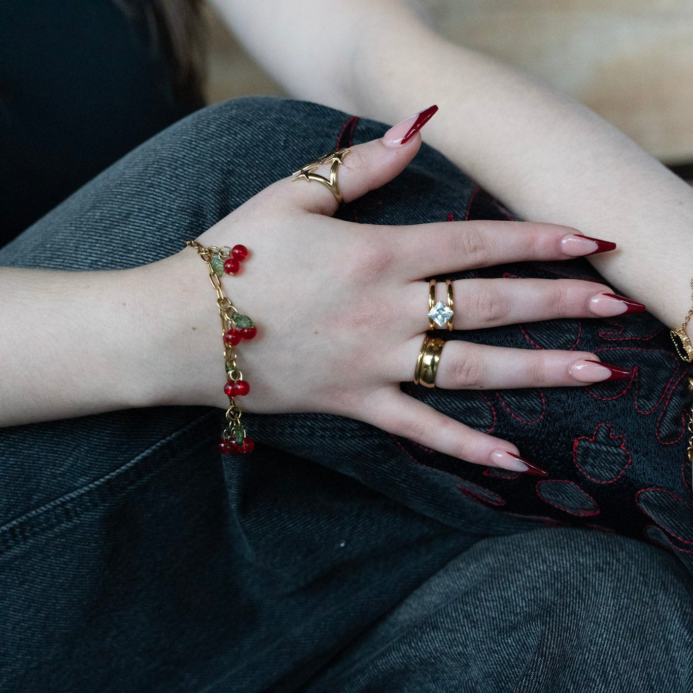 Close-up of hands with multiple bracelets and rings on a wooden surface