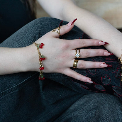 Close-up of hands with multiple bracelets and rings on a wooden surface