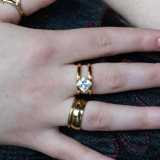 Close-up of hands with multiple bracelets and rings on a wooden surface
