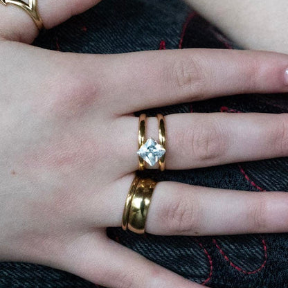 Close-up of hands with multiple bracelets and rings on a wooden surface
