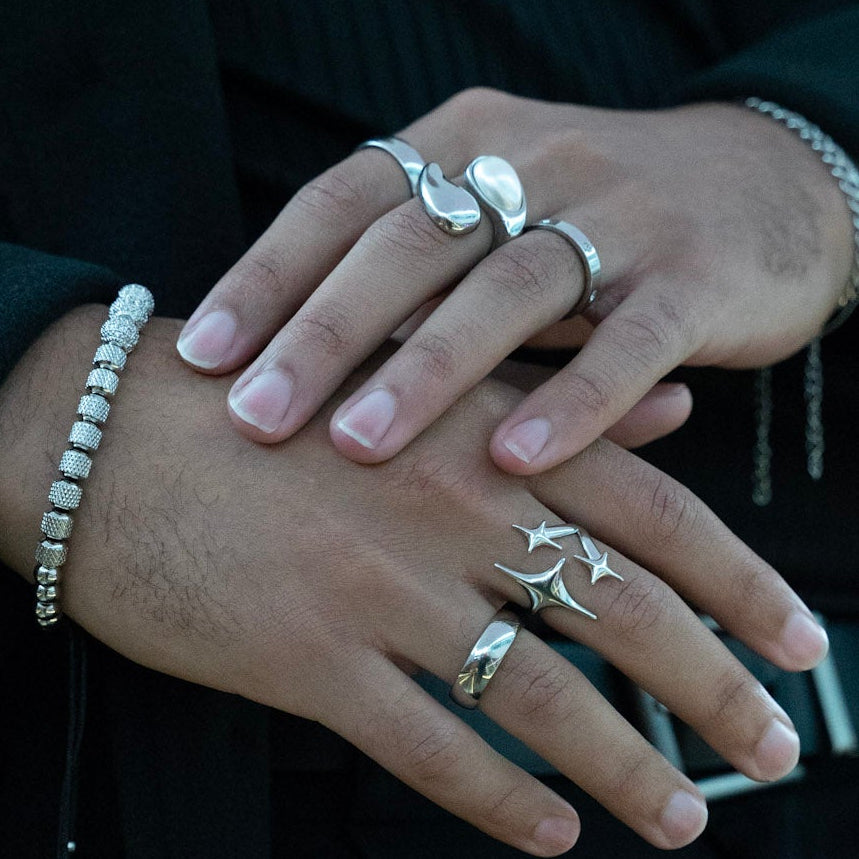 Close-up of hands with multiple rings and bracelets against a dark background