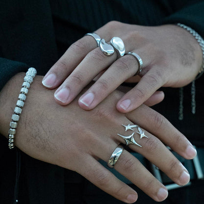 Close-up of hands with multiple rings and bracelets against a dark background