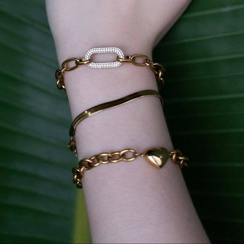 Hand with gold jewelry on a green leaf background