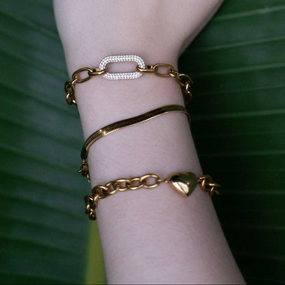Hand with gold jewelry on a green leaf background