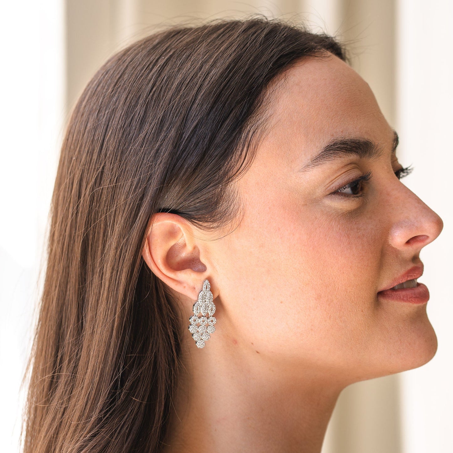 Woman wearing a sparkling earring with a neutral background