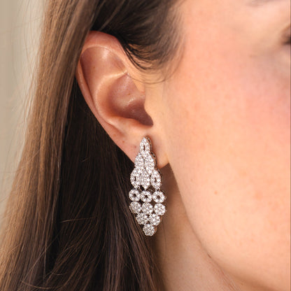 Close-up of a woman wearing a sparkling earring with a neutral background