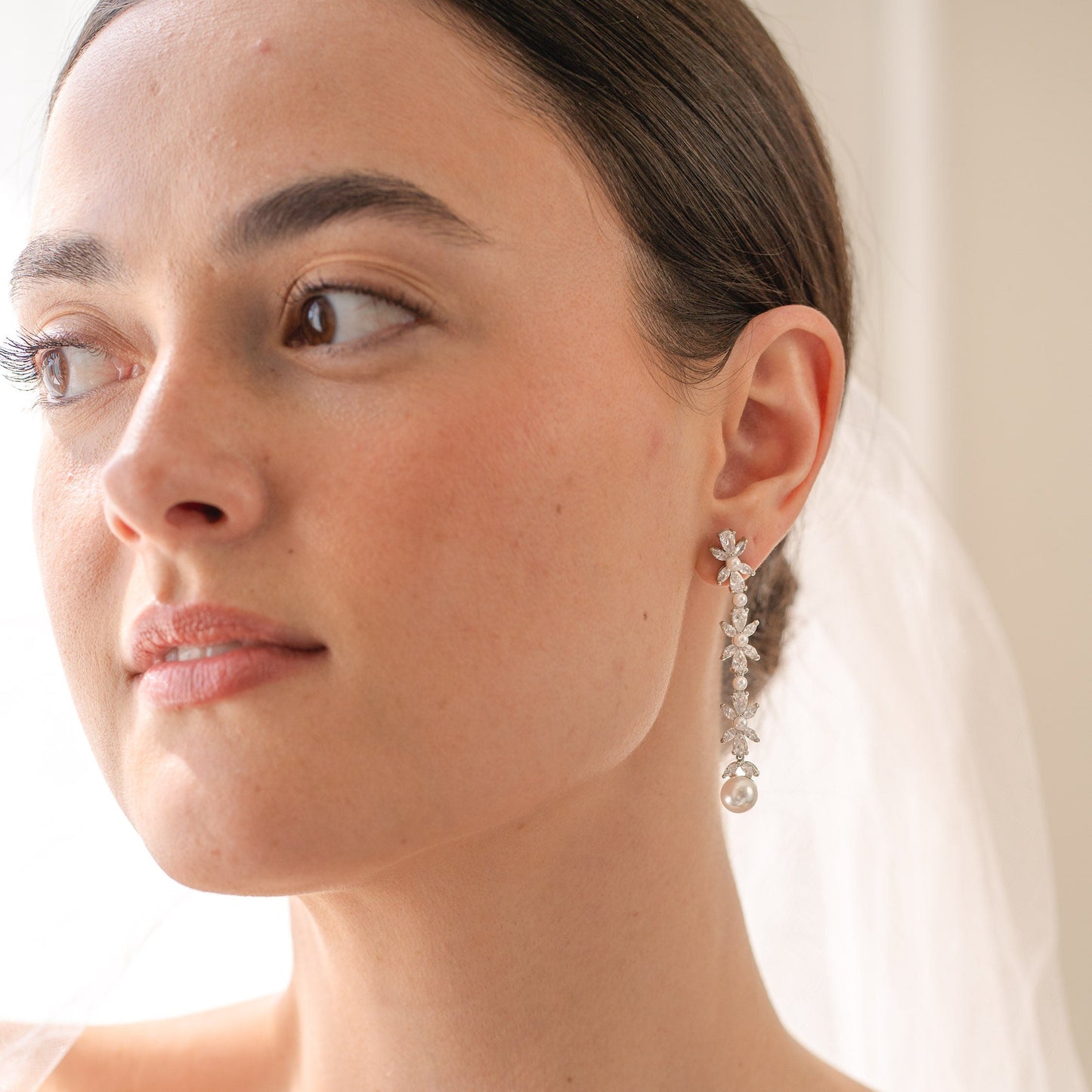 Close-up of a woman wearing a delicate earring with a soft background