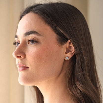 Woman wearing diamond earrings with a neutral background
