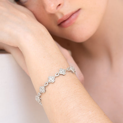 Woman wearing a silver bracelet with floral designs on a light background