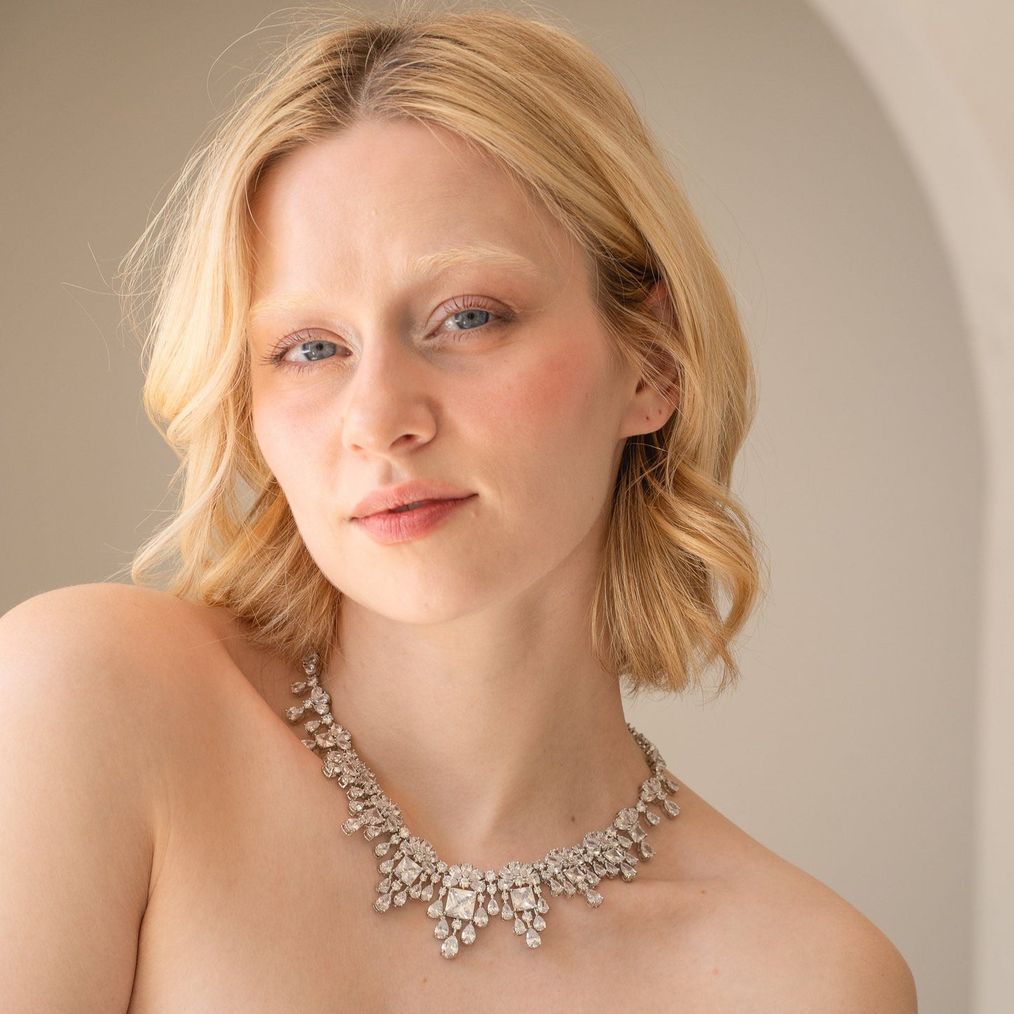 Woman wearing a sparkling necklace against a neutral background