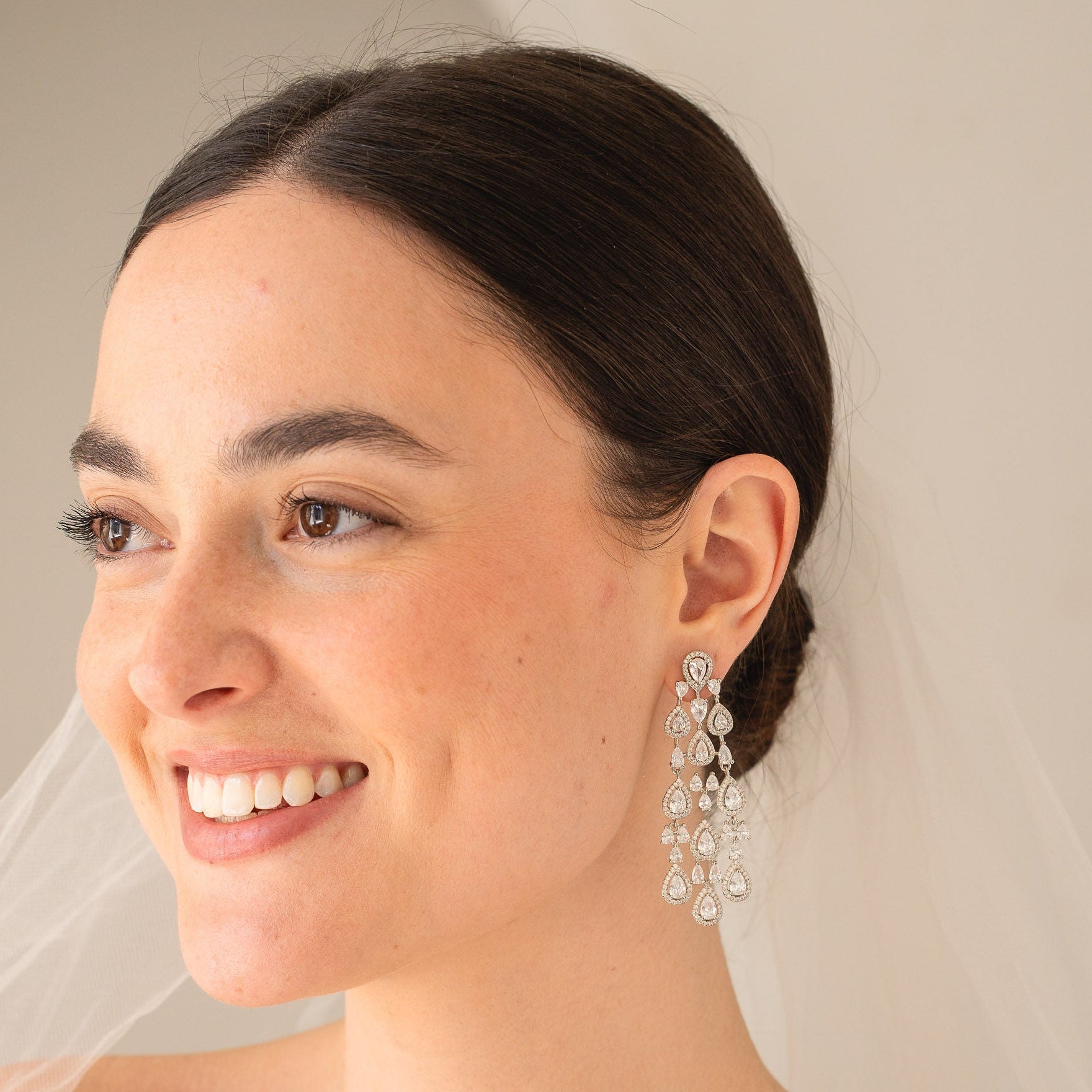 Woman wearing a veil and earrings with a neutral background