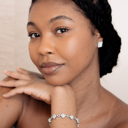Woman with braided hair wearing earrings and a bracelet against a plain background