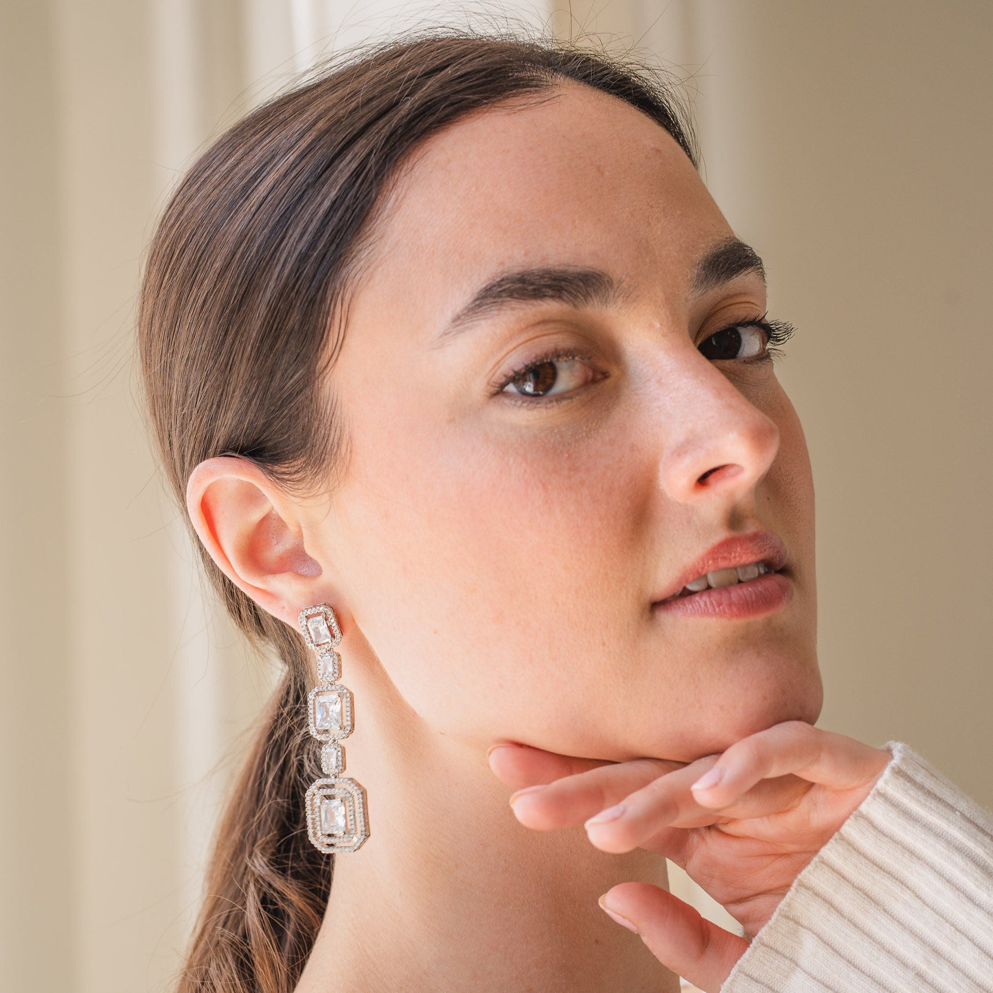 Woman wearing a pair of earrings with a neutral background