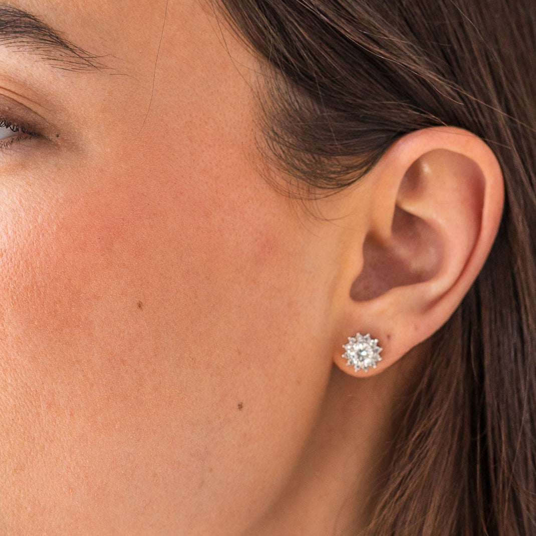 Close-up of a woman wearing a diamond earring with a neutral background