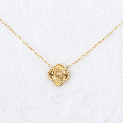 Gold necklace with a circular pendant on a white textured background
