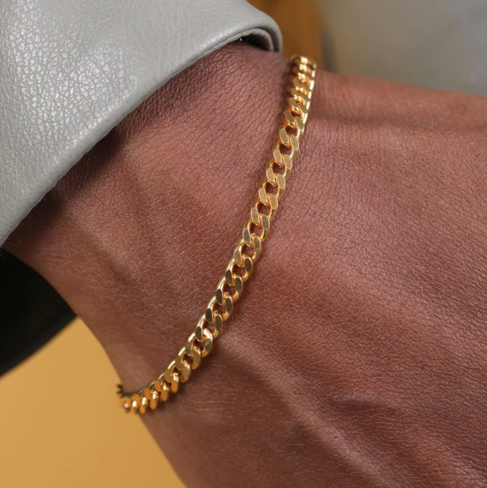 Gold chain bracelet on a wrist with a blurred background