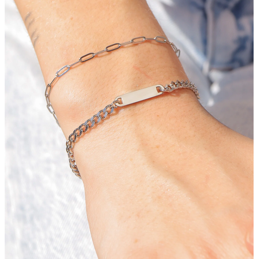 Silver Bracelets on a person's wrist against a neutral background