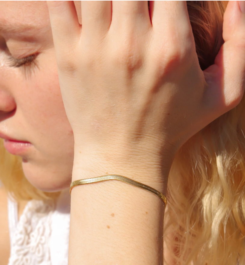 Close-up of a person wearing a gold bracelet on a blurred background