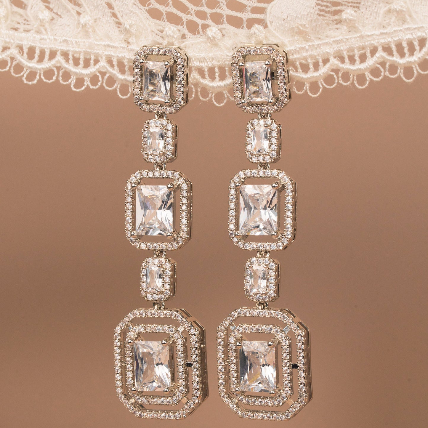 Diamond earrings on a lace fabric background