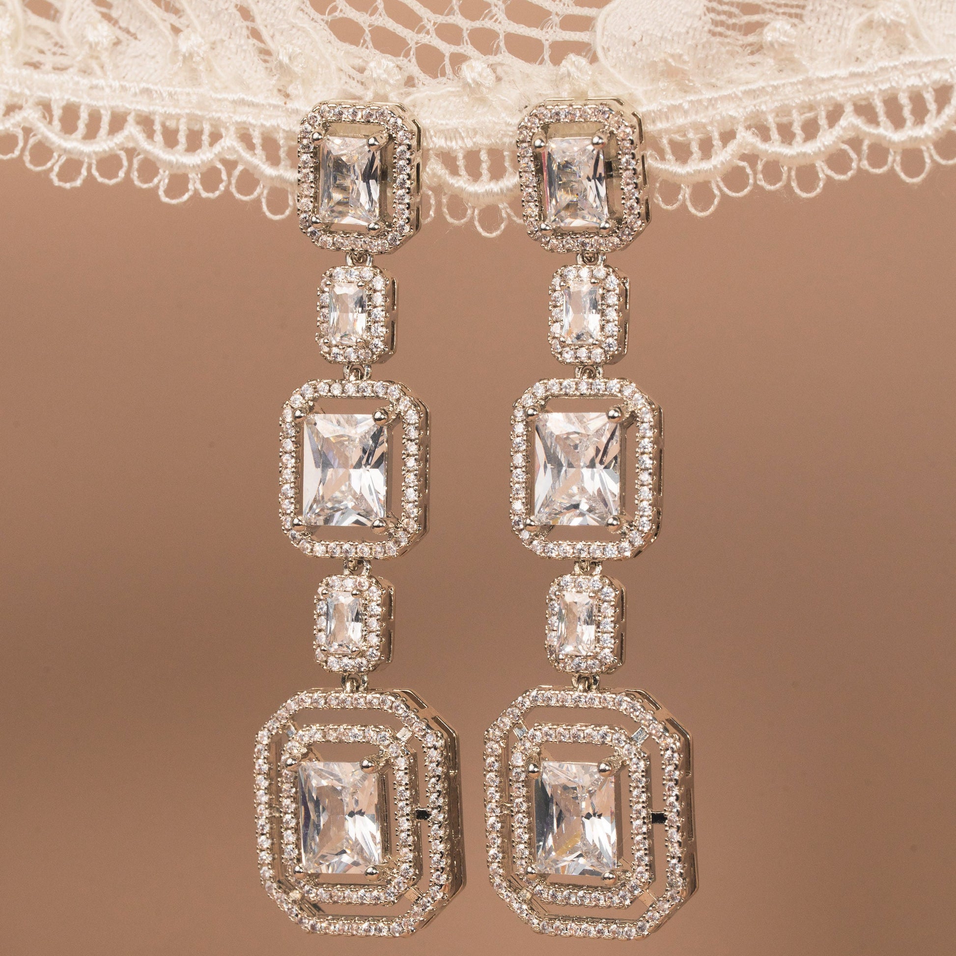 Diamond earrings on a lace fabric background