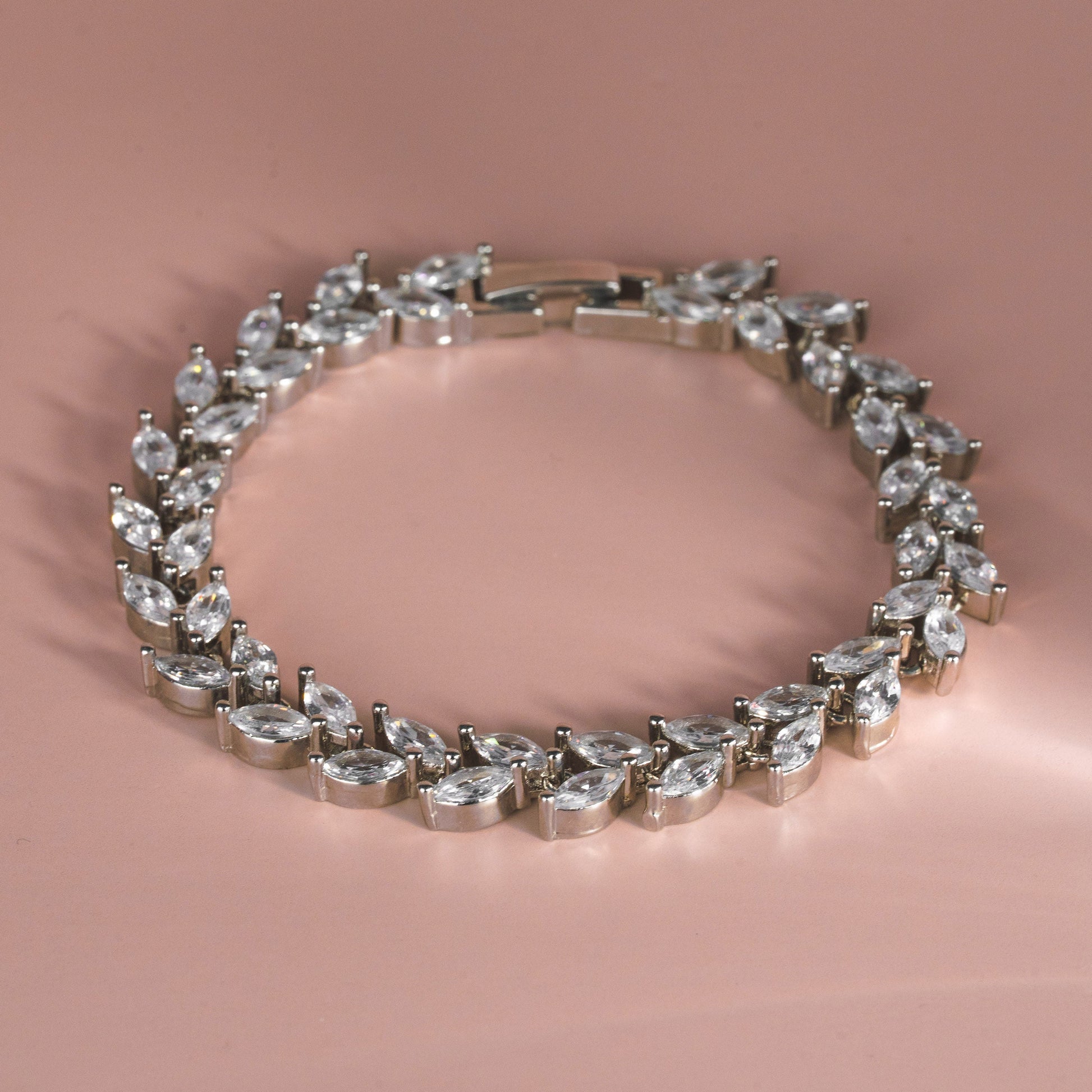 Teardrop-shaped diamond bracelet on a pink background