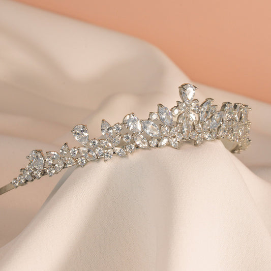 Silver tiara with clear stones on a soft pink fabric background