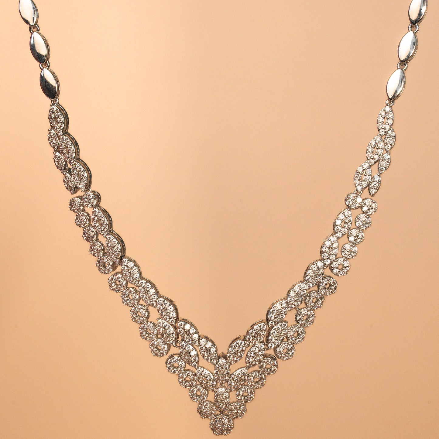 Silver necklace with intricate design on a beige background