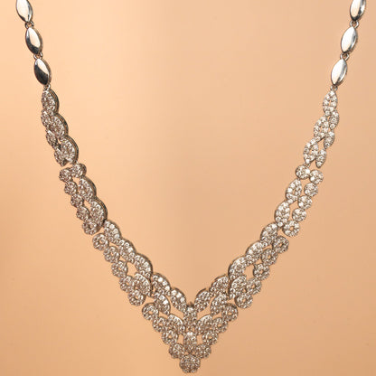 Silver necklace with intricate design on a beige background