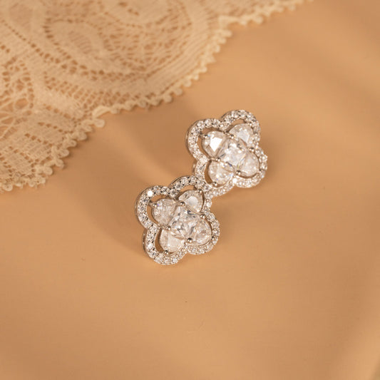 Decorative silver earrings on a beige lace fabric background