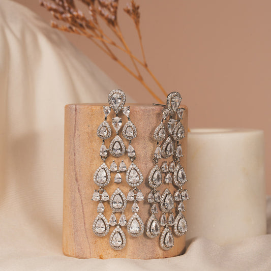 Pair of silver earrings on a wooden block with a neutral background